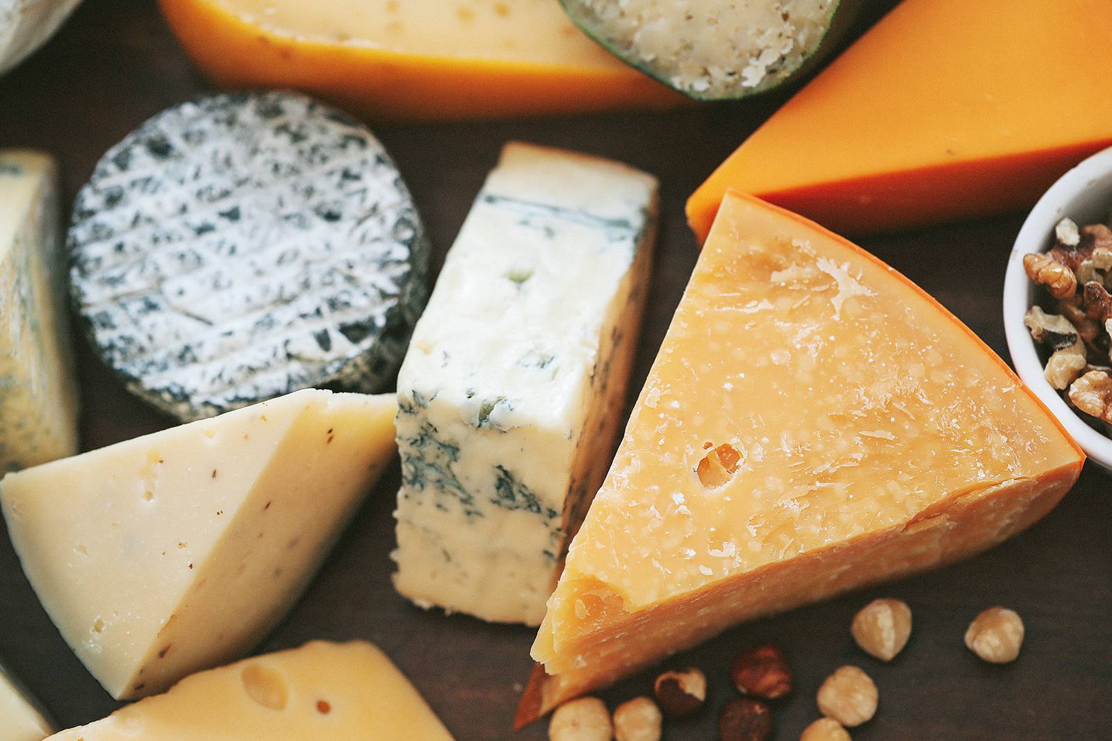 Assorted cheeses with nuts on wooden board