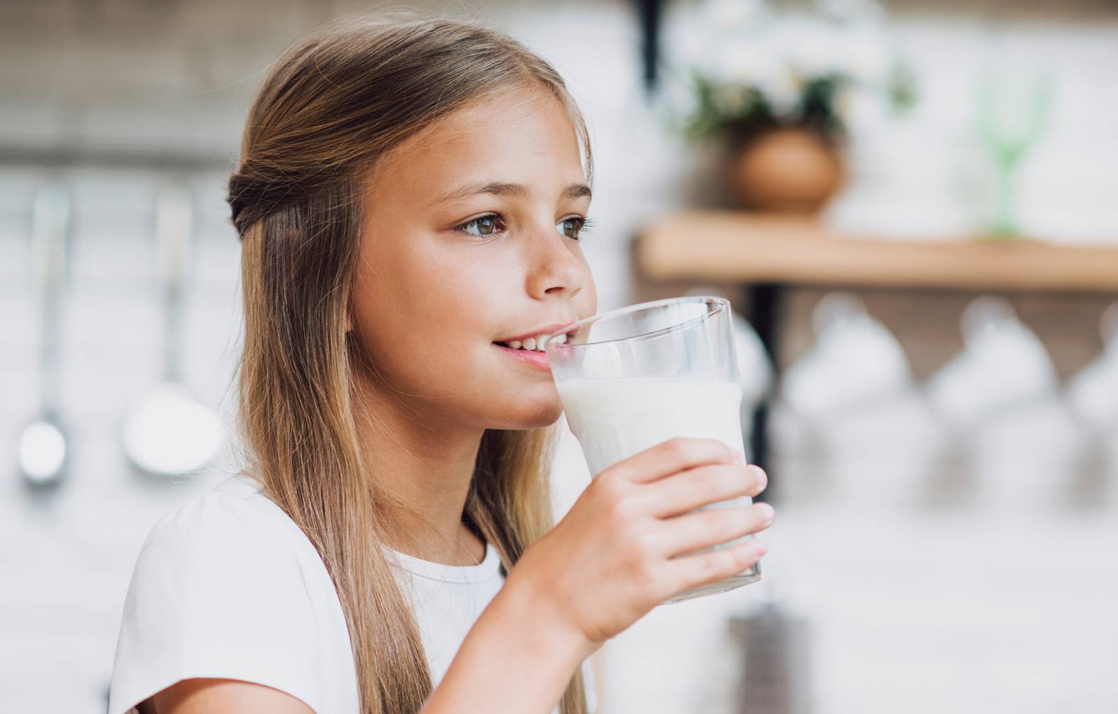 Child sipping milk in kitchen