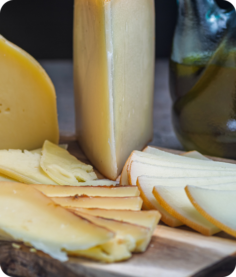 Assorted cheese slices on wooden board.