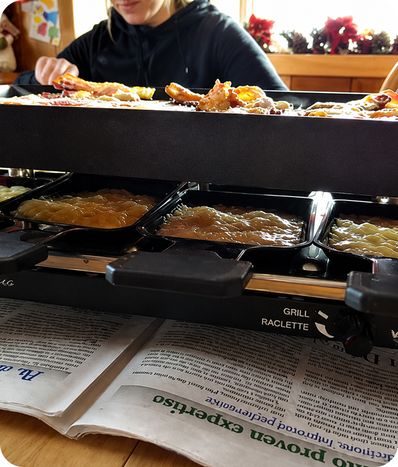 Raclette grill with food and melted cheese.