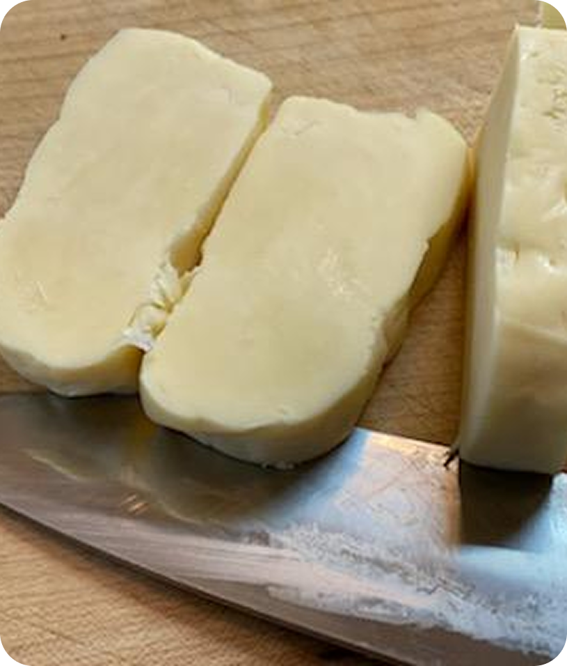 Sliced cheese on cutting board with knife.